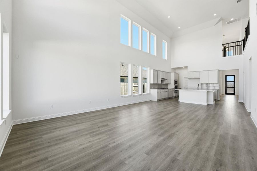 Unfurnished living room with dark wood-style flooring and a high ceiling