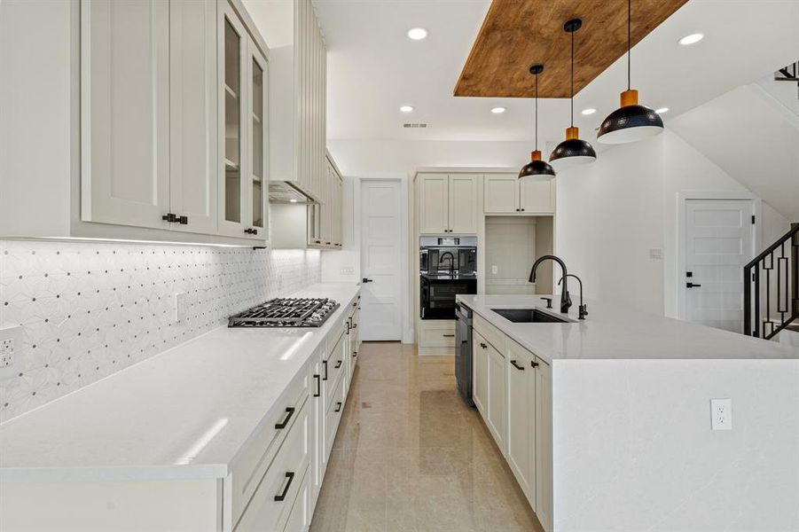 Kitchen with tasteful backsplash, recessed lighting, gas cooktop, multiple ovens, and a sink