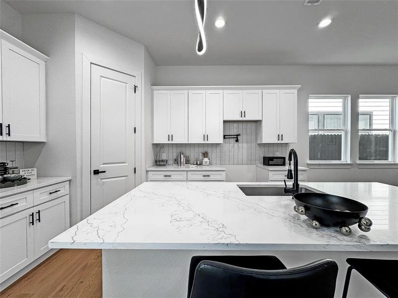 Kitchen featuring backsplash and white cabinets