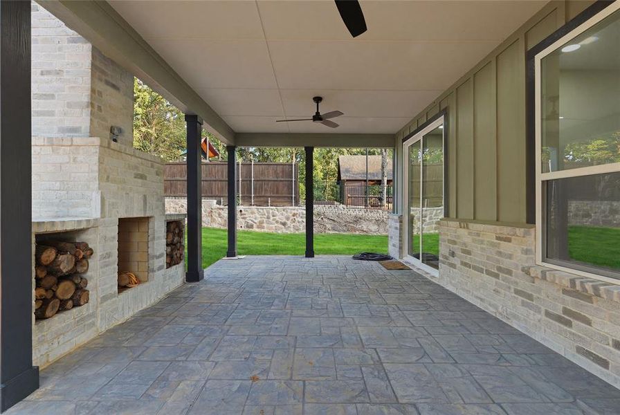 Covered patio featuring stamped concrete flooring and a white brick fireplace with integrated wood storage Covered patio featuring stamped concrete flooring and a white brick fireplace with integrated wood storage