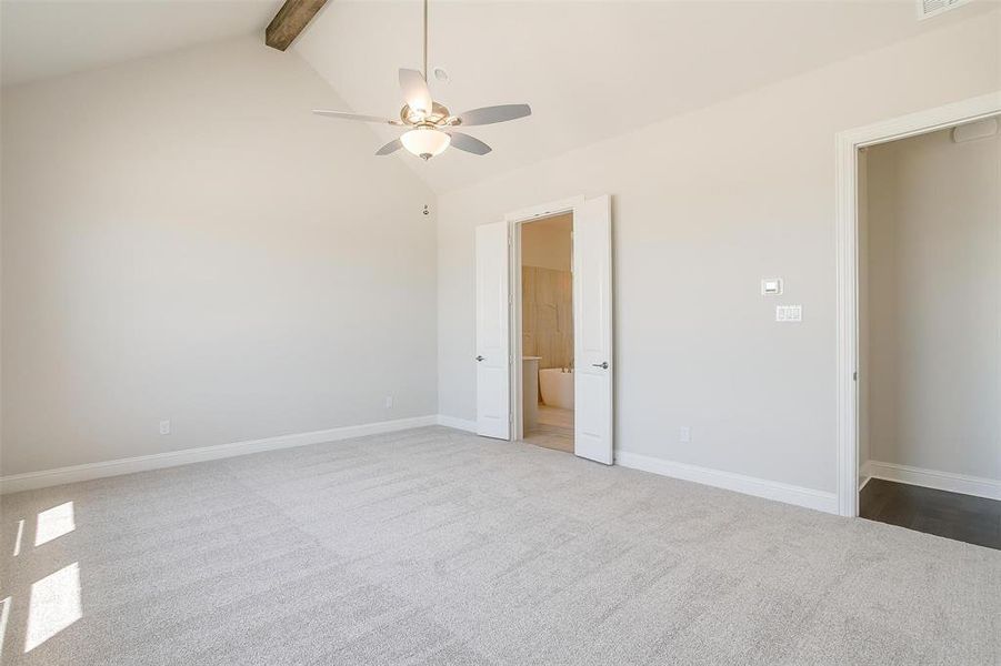 Unfurnished bedroom featuring beam ceiling, high vaulted ceiling, carpet floors, and ceiling fan