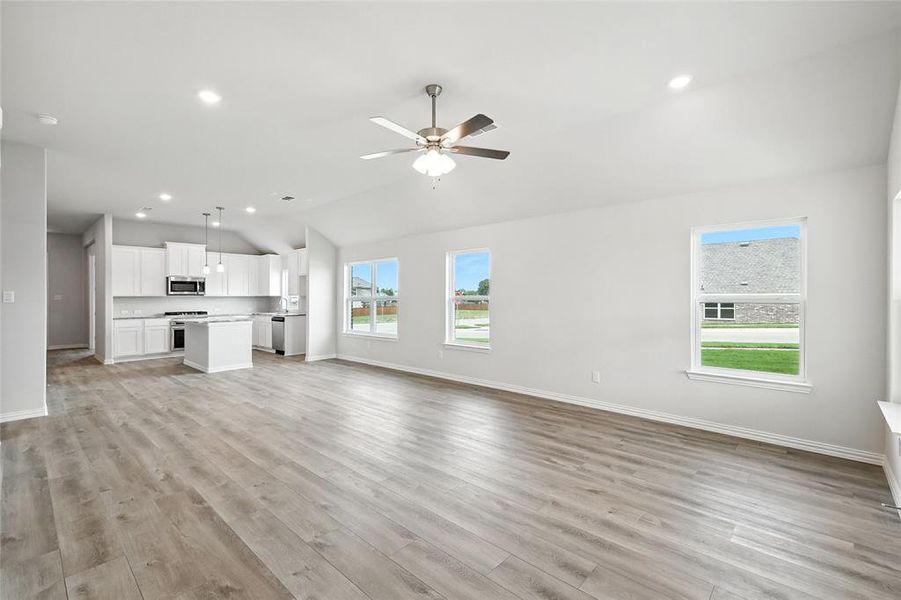 Unfurnished living room with lofted ceiling, light wood-style floors, a ceiling fan, and recessed lighting