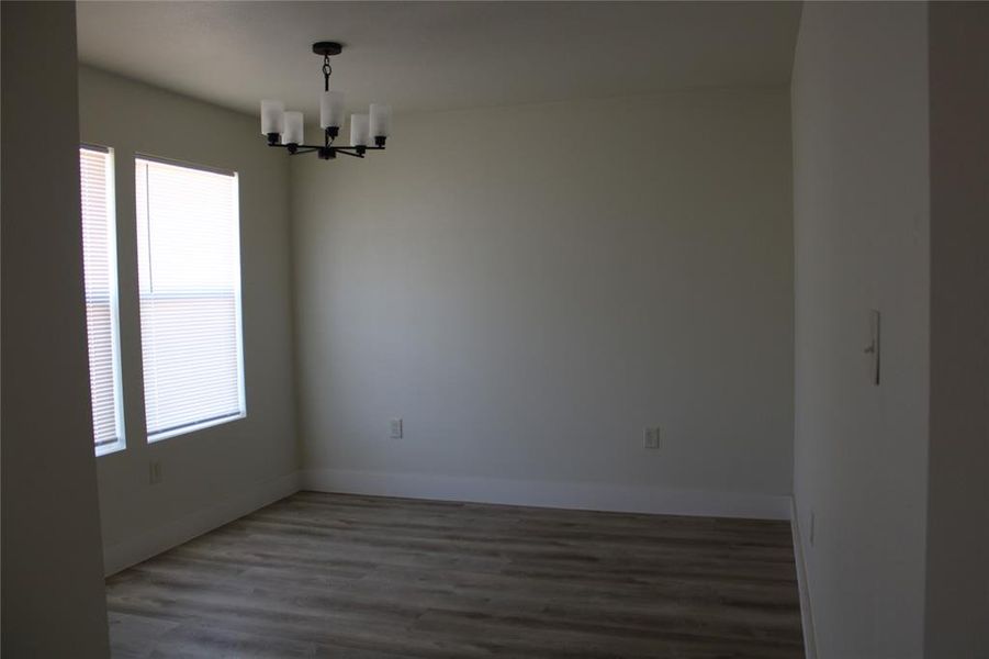 Unfurnished room featuring dark wood-type flooring and a chandelier