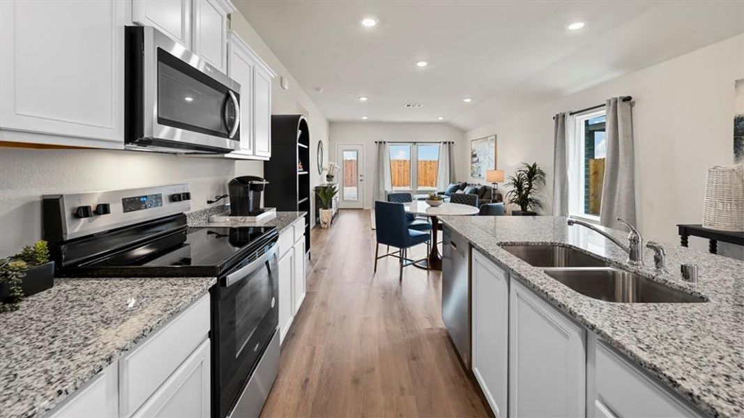 Kitchen with appliances with stainless steel finishes, white cabinetry, dark wood finished floors, light stone countertops, and recessed lighting Kitchen with appliances with stainless steel finishes, white cabinetry, dark wood finished floors, light stone countertops, and recessed lighting