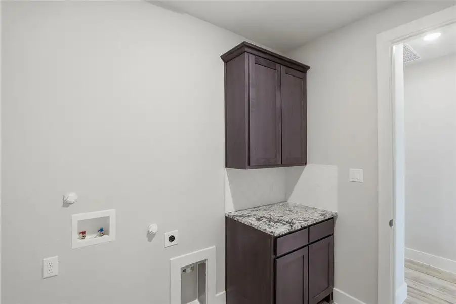 Laundry room with cabinet space, hookup for a gas dryer, electric dryer hookup, hookup for a washing machine, and light wood-style flooring