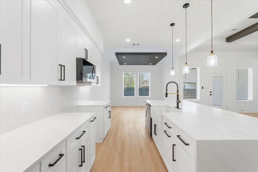 The ample kitchen offers generous storage, neutral black-and-white finishes, quartz countertops and backsplash, as well as under-cabinet lighting.