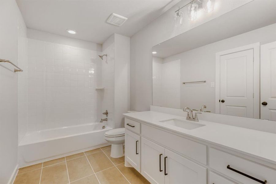 Bathroom featuring shower / bathtub combination, vanity, light tile patterned floors, and recessed lighting