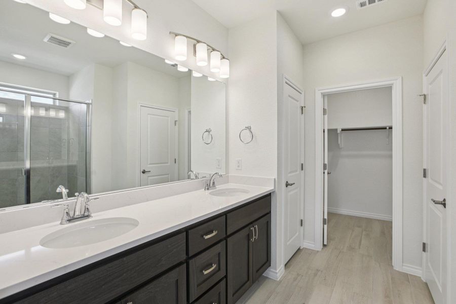 Full bath featuring a stall shower, recessed lighting, double vanity, a spacious closet, and light wood-style flooring