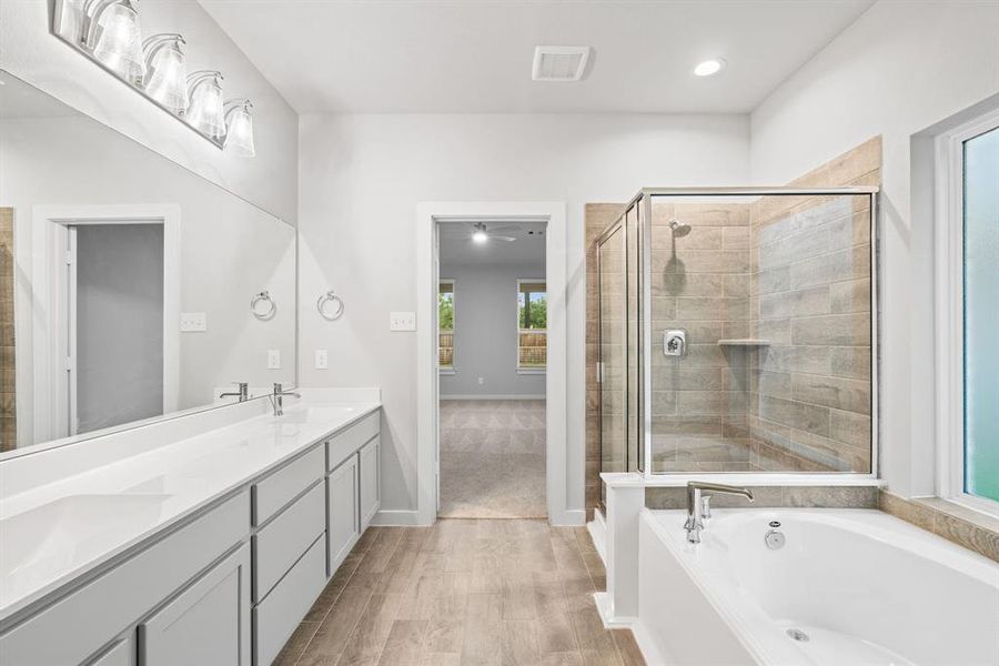 Elevate your daily routine at the refined vanity, now boasting double sinks, light-toned countertops, modern hardware, and captivating vanity lights. Sample photo of completed home with similar floor plan. As-built interior colors and selections may vary.