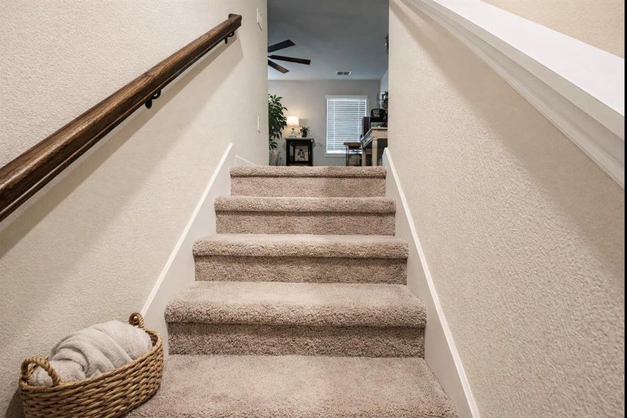 Staircase featuring a textured wall and a ceiling fan