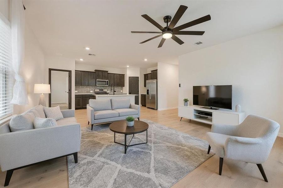 Living room with a ceiling fan, light wood-style floors, and recessed lighting