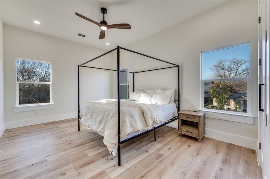 Bedroom featuring light wood-style floors, ceiling fan, multiple windows, and recessed lighting