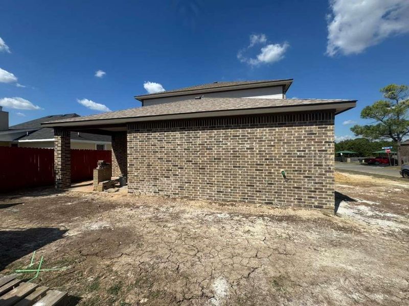 View of back of home with brick siding, a patio area, and a shingled roof View of back of home with brick siding, a patio area, and a shingled roof