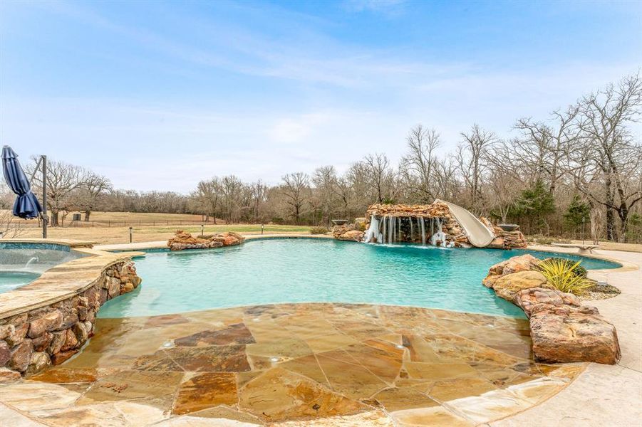 View of swimming pool featuring a water slide, a patio area, and a pool with connected hot tub