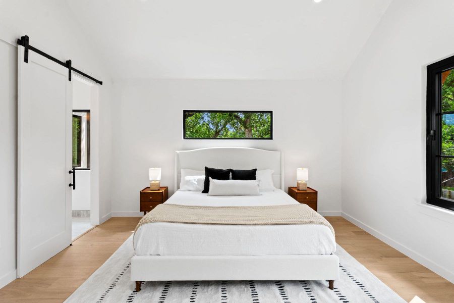 A well-lit bedroom features hardwood floors and a sleek barn door, creating a modern retreat. A well-lit bedroom features hardwood floors and a sleek barn door, creating a modern retreat.