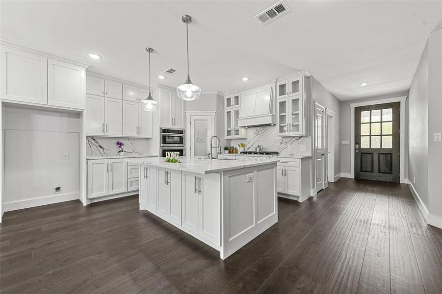 Kitchen with sink, an island with sink, pendant lighting, white cabinets, and dark hardwood / wood-style floors