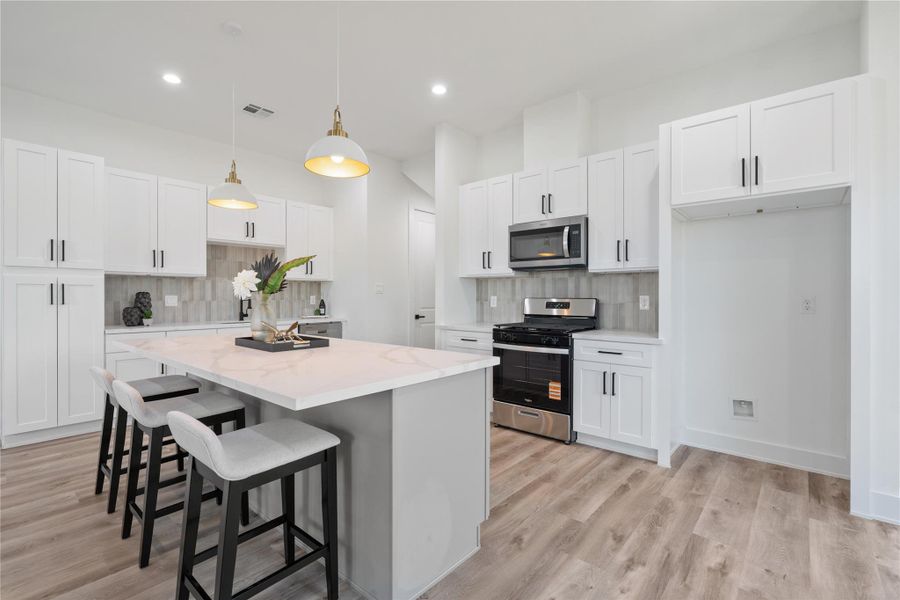 The kitchen features elegant white cabinetry paired with a massive quartz countertops and a gray accent island, combining style and functionality. It’s a bright, inviting space perfect for cooking, entertaining, and gathering with family. The thoughtful design makes both daily life and special occasions effortless.