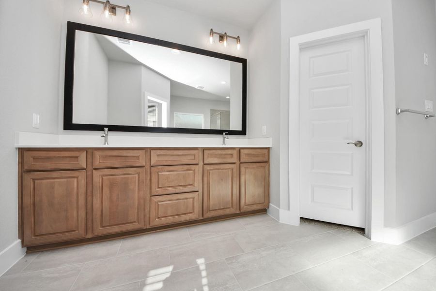 Elevate your daily routine at the elegant vanity, now equipped with double sinks, light countertops, modern hardware, and beautiful vanity lights.