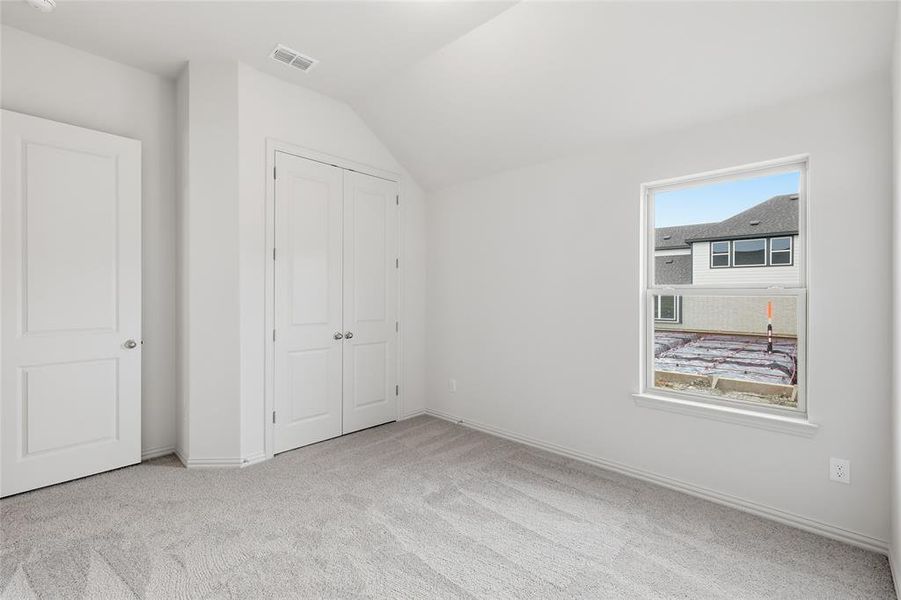 Neutral wall color with plush gray carpet, featuring a single window, a panel door, and bifold closet doors Neutral wall color with plush gray carpet, featuring a single window, a panel door, and bifold closet doors
