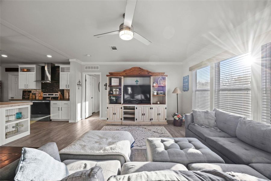 Living room featuring ceiling fan, crown molding, wood finished floors, and recessed lighting