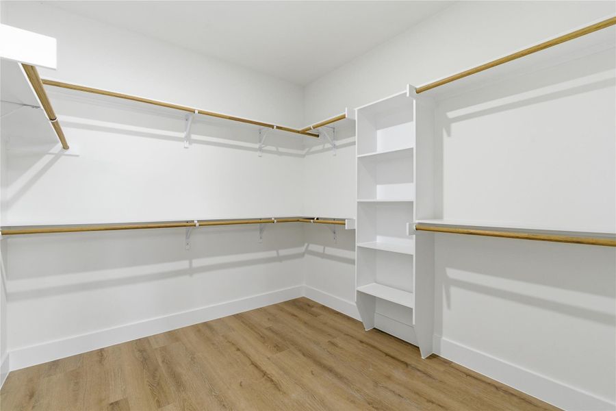 An oversized primary walk-in closet offers abundant hanging space and built-in shelving for effortless organization.