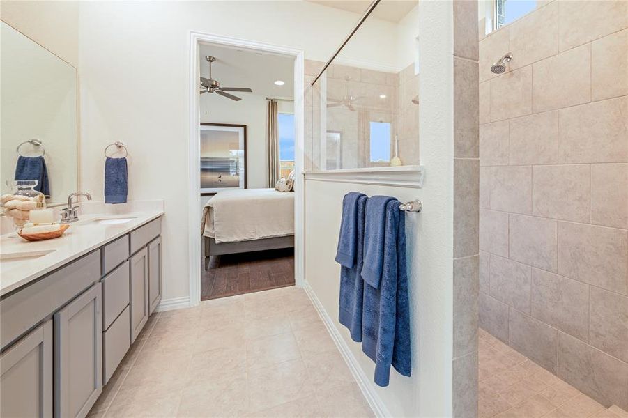 Bathroom featuring a walk in shower, ensuite bath, double vanity, light tile patterned flooring, and a ceiling fan