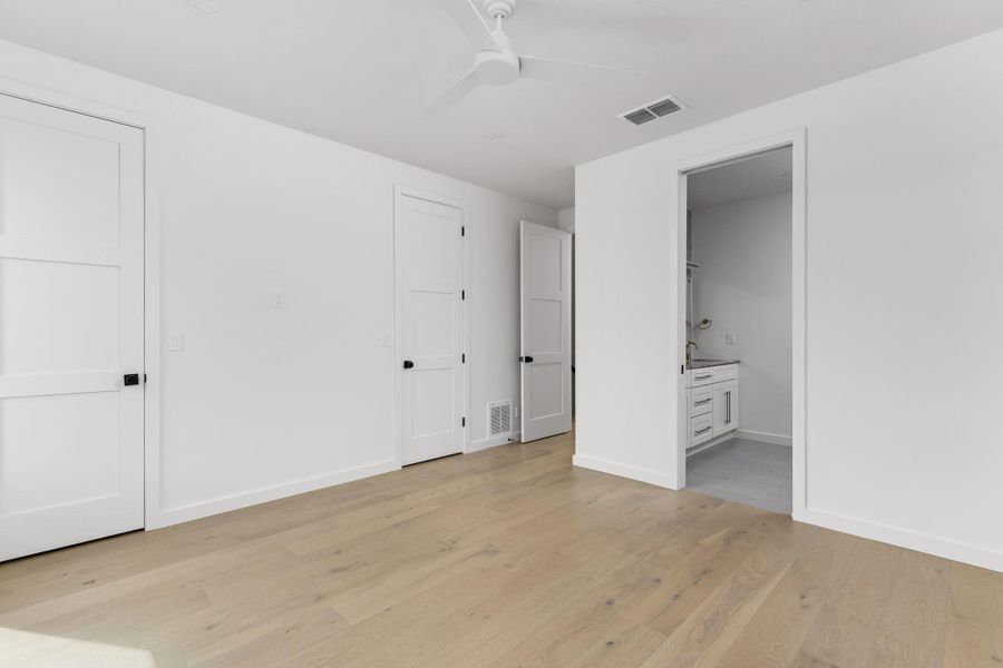 Unfurnished bedroom with light wood-style flooring, connected bathroom, and ceiling fan