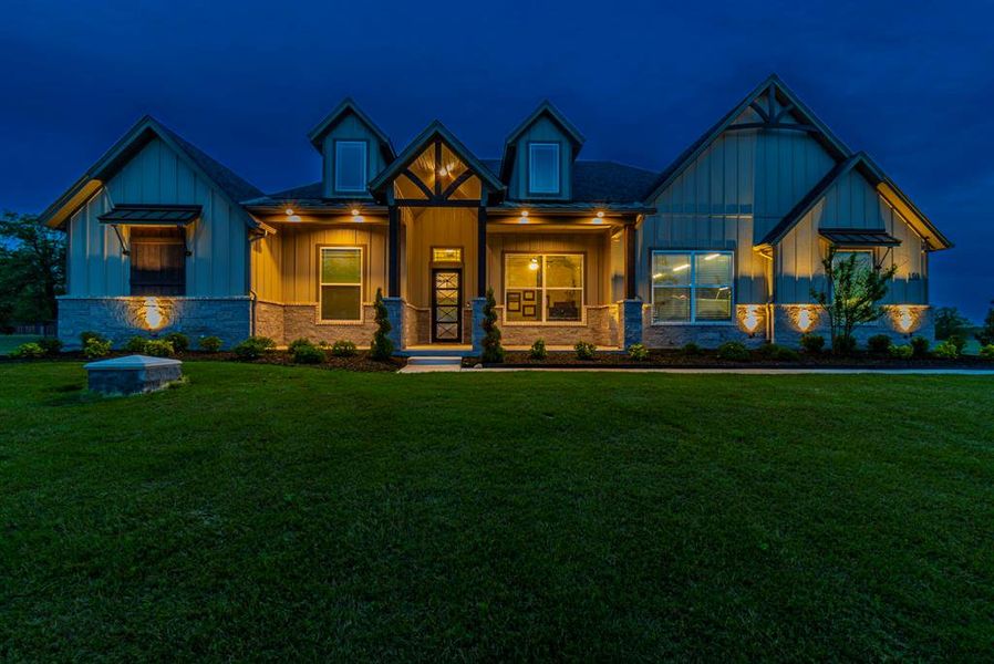 Craftsman-style home with covered porch, board and batten siding, stone siding, and a lawn Craftsman-style home with covered porch, board and batten siding, stone siding, and a lawn