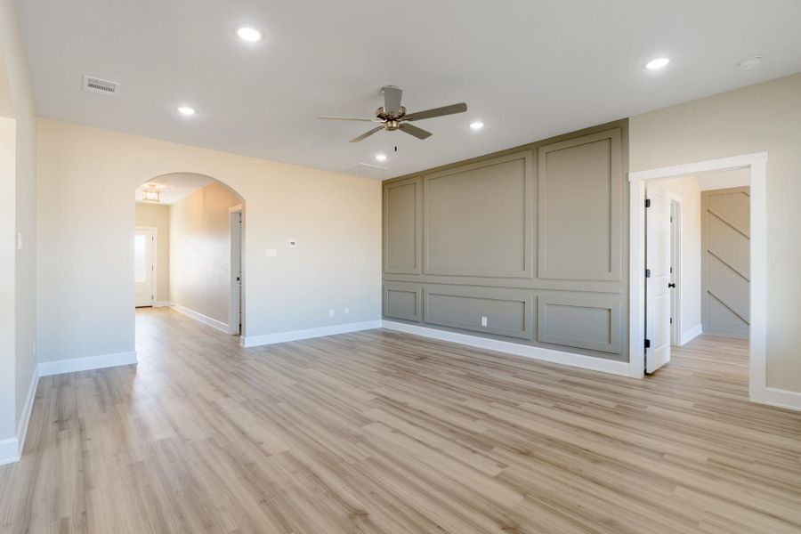 Empty room with arched walkways, ceiling fan, light wood-style flooring, and recessed lighting