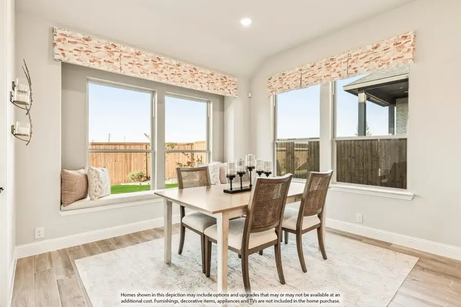 Bright dining area with wood table, cane chairs, window seat, and large windows overlooking backyard