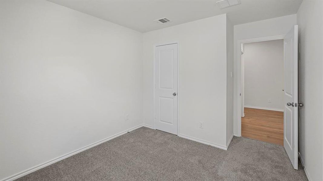 Carpeted room with white walls, white baseboards, and a white paneled door with a chrome knob