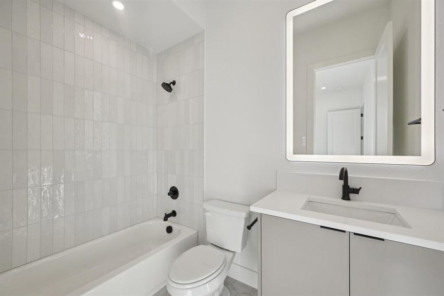 Full bathroom with tiled shower / bath, vanity, and toilet