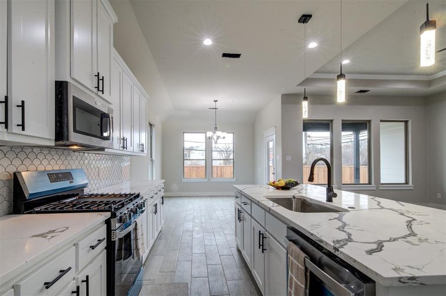 Kitchen with appliances with stainless steel finishes, an island with sink, and white cabinets