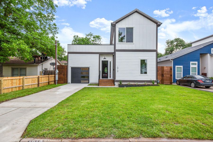 View of front facade with a garage, concrete driveway, fence, a front lawn, and board and batten siding