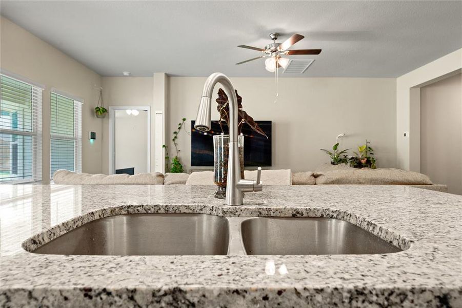 Kitchen view of light stone counters and ceiling fan