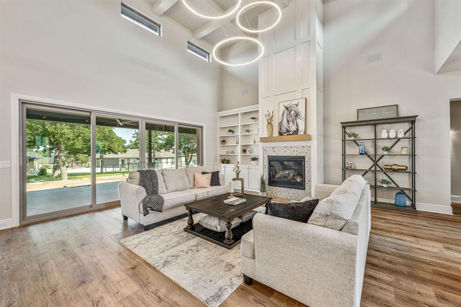 Living room with an inviting chandelier, hardwood / wood-style flooring, built in shelves, and a high ceiling