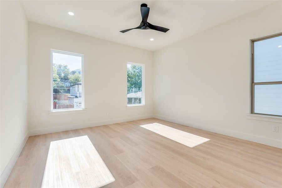 Empty room with ceiling fan and light hardwood / wood-style floors