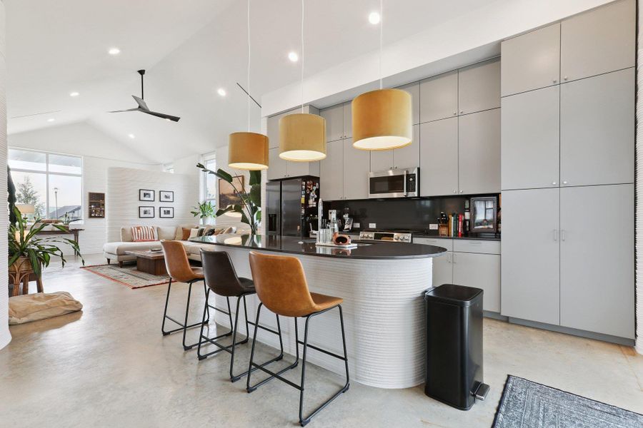 Kitchen with open floor plan, stainless steel appliances, a high ceiling, ceiling fan, and concrete floors
