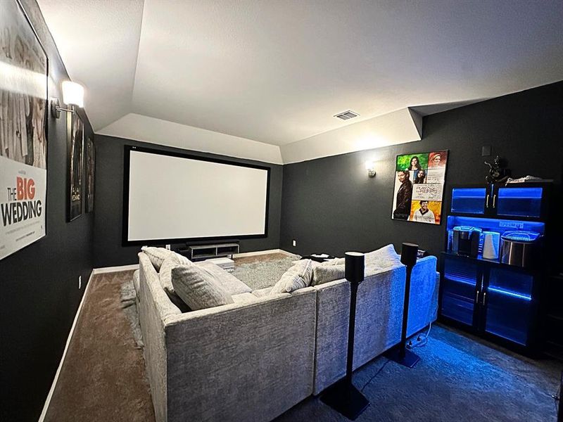 Theater room with lofted ceiling and baseboards
