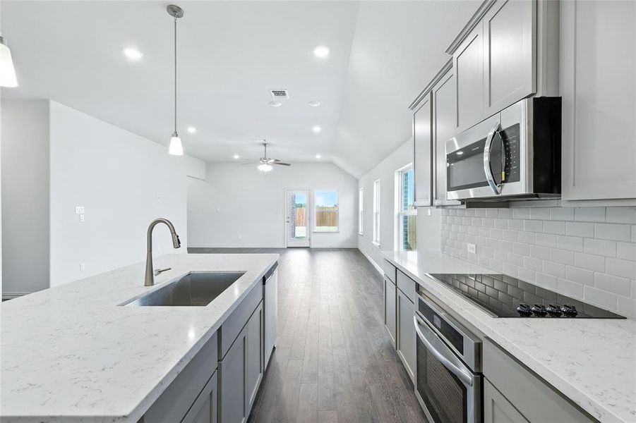 Kitchen with gray cabinetry, light stone countertops, a center island with sink, stainless steel appliances, and recessed lighting Kitchen with gray cabinetry, light stone countertops, a center island with sink, stainless steel appliances, and recessed lighting