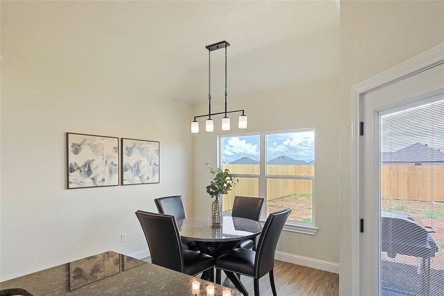 Dining area featuring a contemporary linear chandelier, multiple windows, and light wood-finish flooring