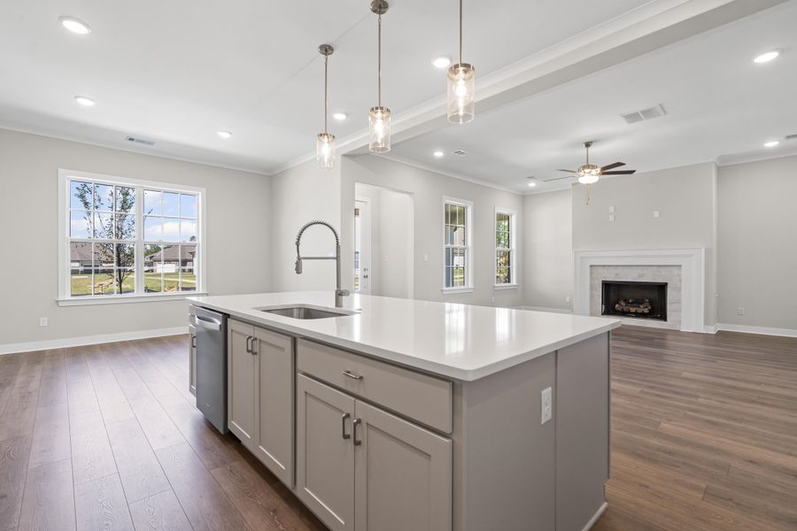 Kitchen with gray cabinetry island, open floor plan, ornamental molding, hanging light fixtures, and recessed lighting