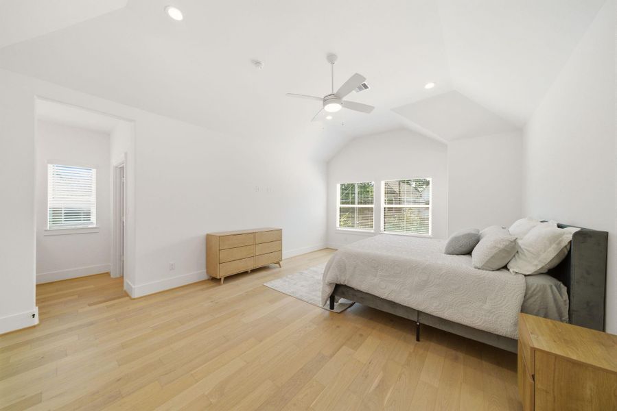 Expansive primary suite featuringvaulted ceilings, abundant naturallight, an oversized layout, andseamless access to the adjoiningvanity area, walk-in closet and en-suite bath. (Photo of a previous build, similar finishes.)