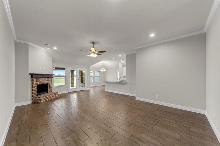 Expansive living area featuring wood-finish tile flooring and a brick fireplace with a dark wood mantel