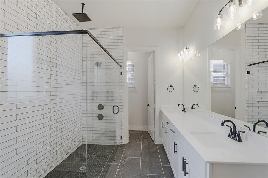 Bathroom with a stall shower, double vanity, and dark marble finish flooring