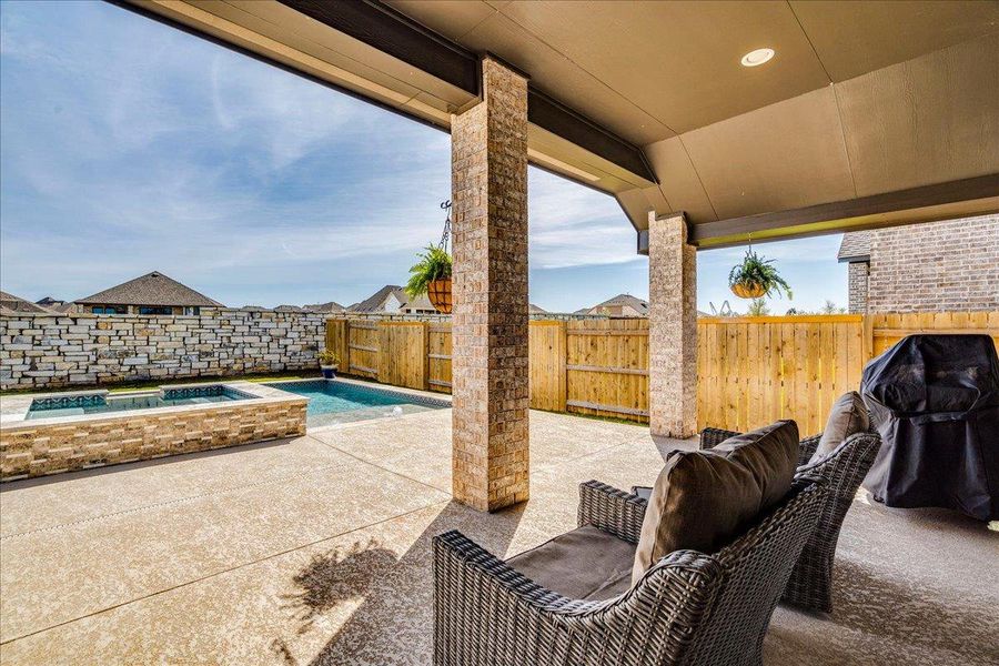 Fenced backyard with a patio and a pool with connected hot tub