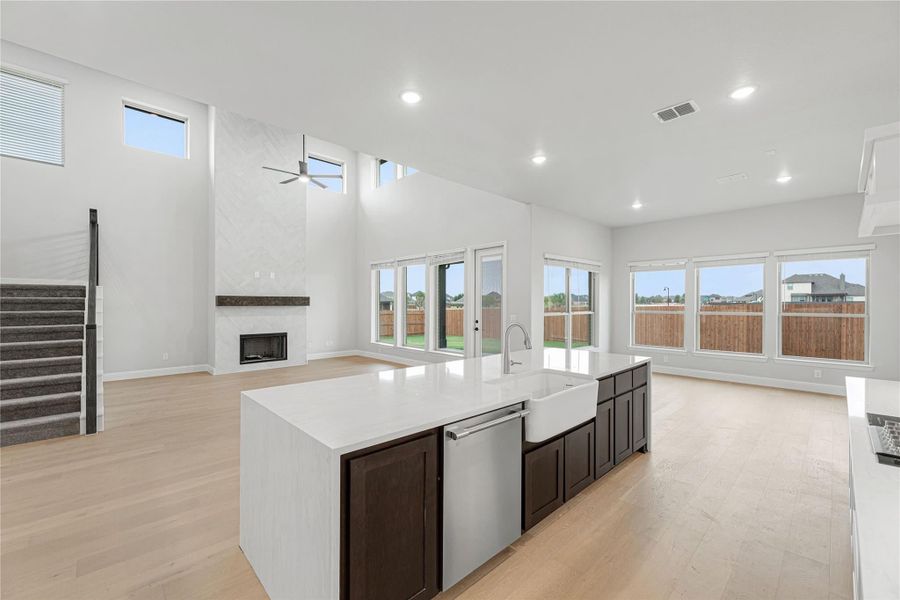 Open-concept kitchen with large island, farmhouse sink, and living area with fireplace and high ceilings