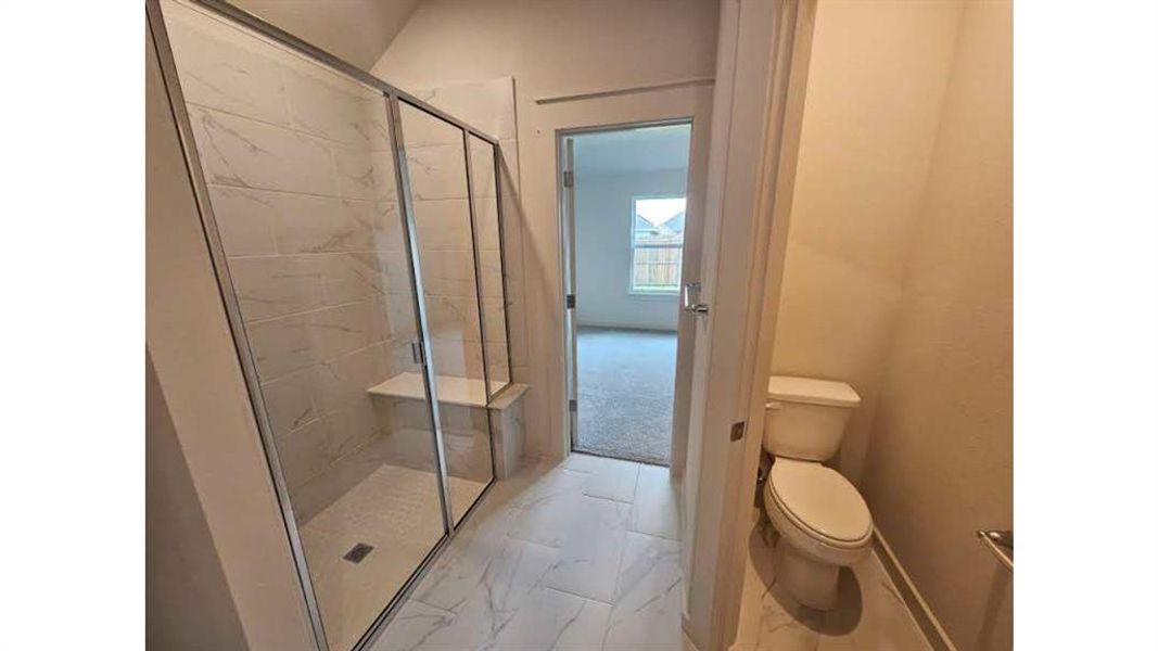 Walk-in shower with clear glass enclosure and built-in bench