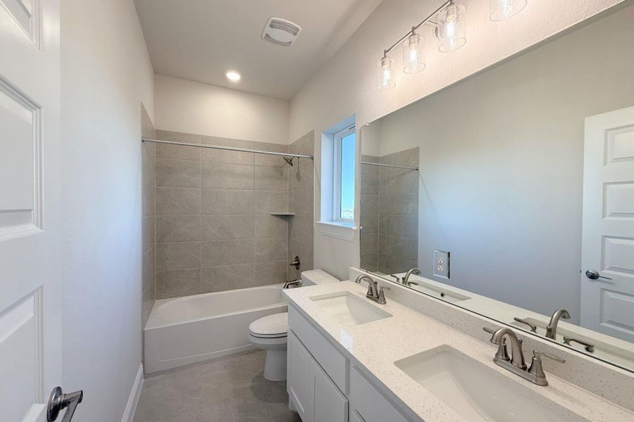 Full bathroom featuring double vanity, bathtub / shower combination, and light tile patterned flooring