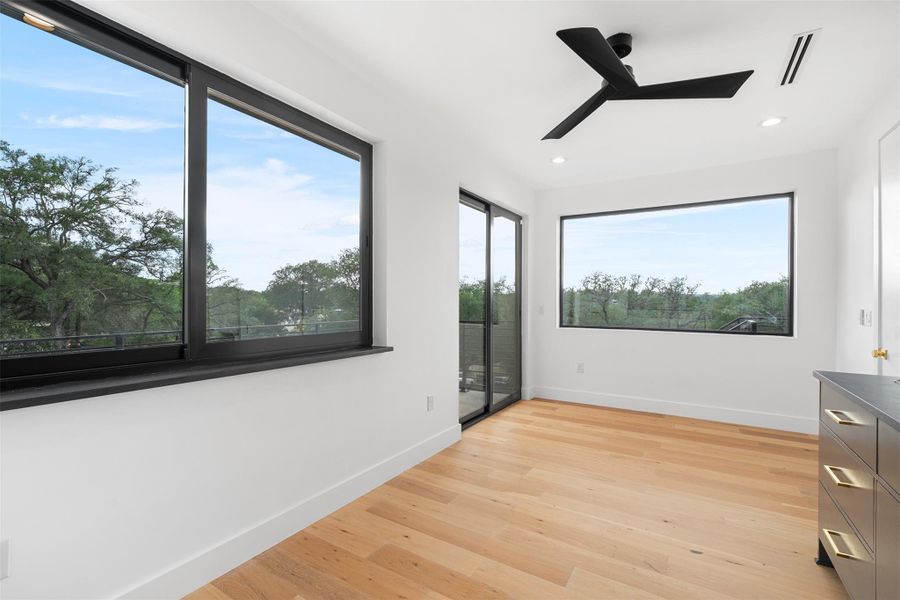 This bright space features light hardwood flooring and white walls, complemented by a contemporary black ceiling fan
